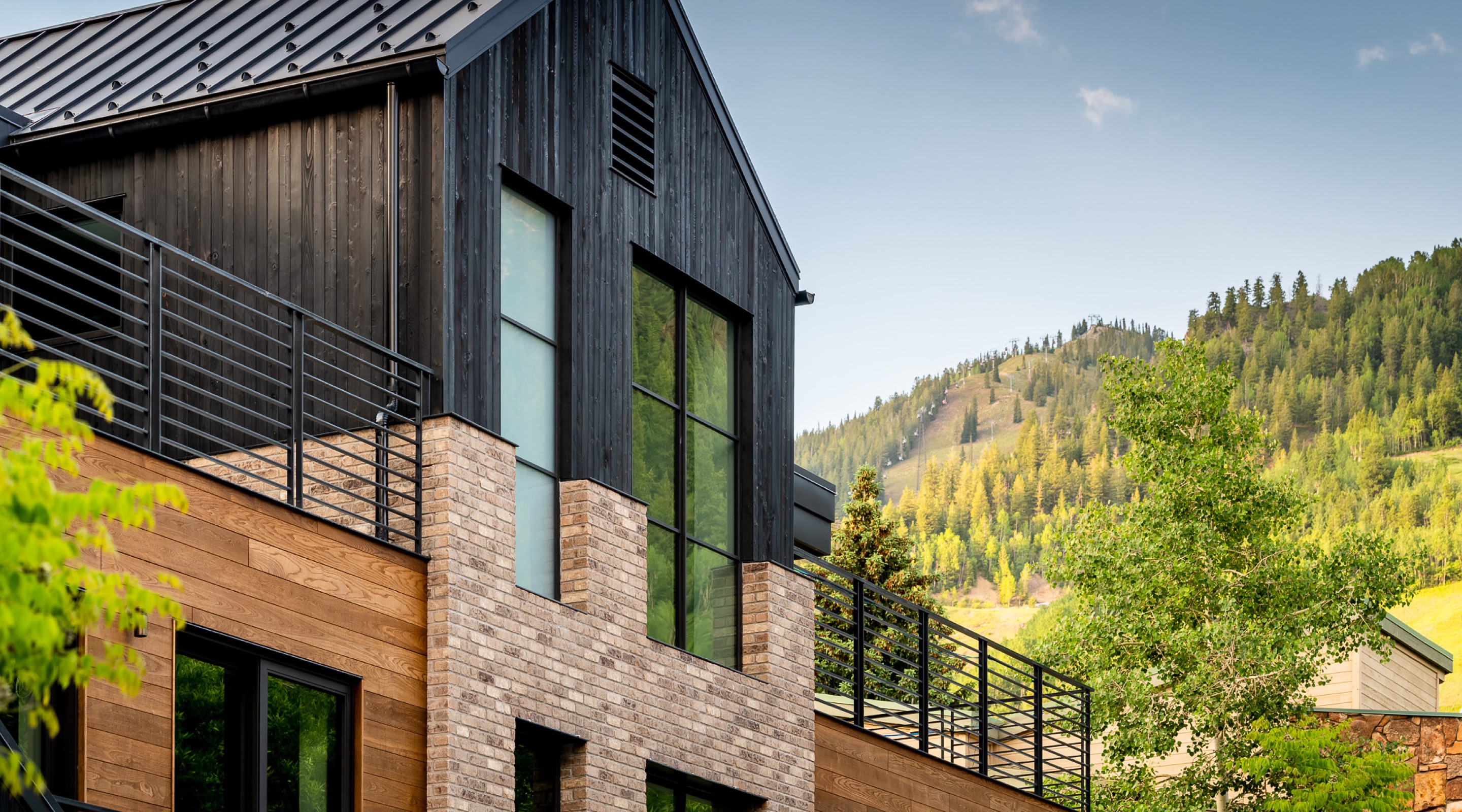 Exterior of Aspen luxury rental second level with large windows, decks and Aspen mountain in the background