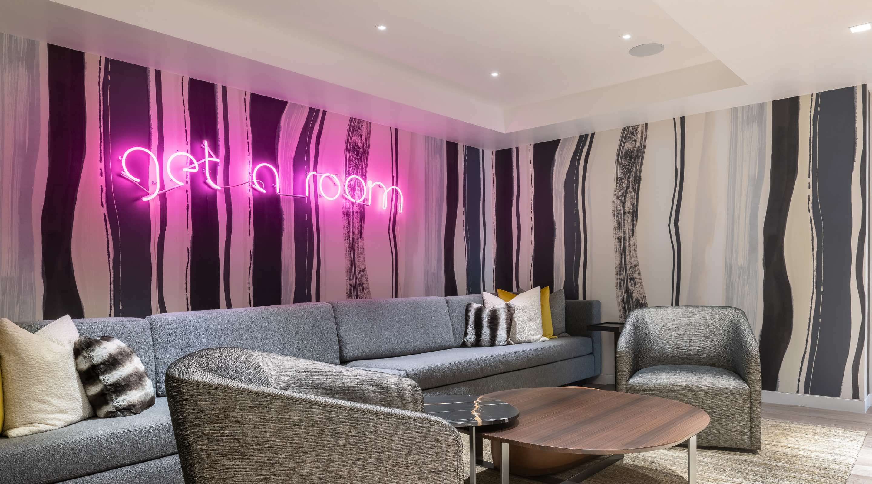 Common area living room with "get a room" neon sign at Aspen Street Lodge corporate retreat venue in Aspen