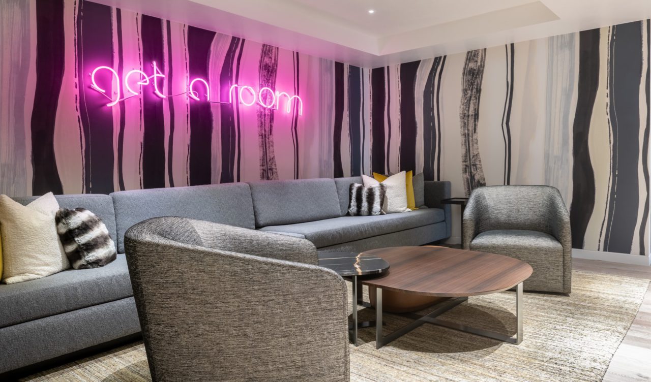 Common area living room with "get a room" neon sign at Aspen Street Lodge corporate retreat venue in Aspen