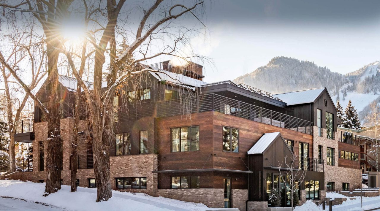 Exterior side view of Aspen Street Lodge with snow on ground and roof and Aspen mountain in background