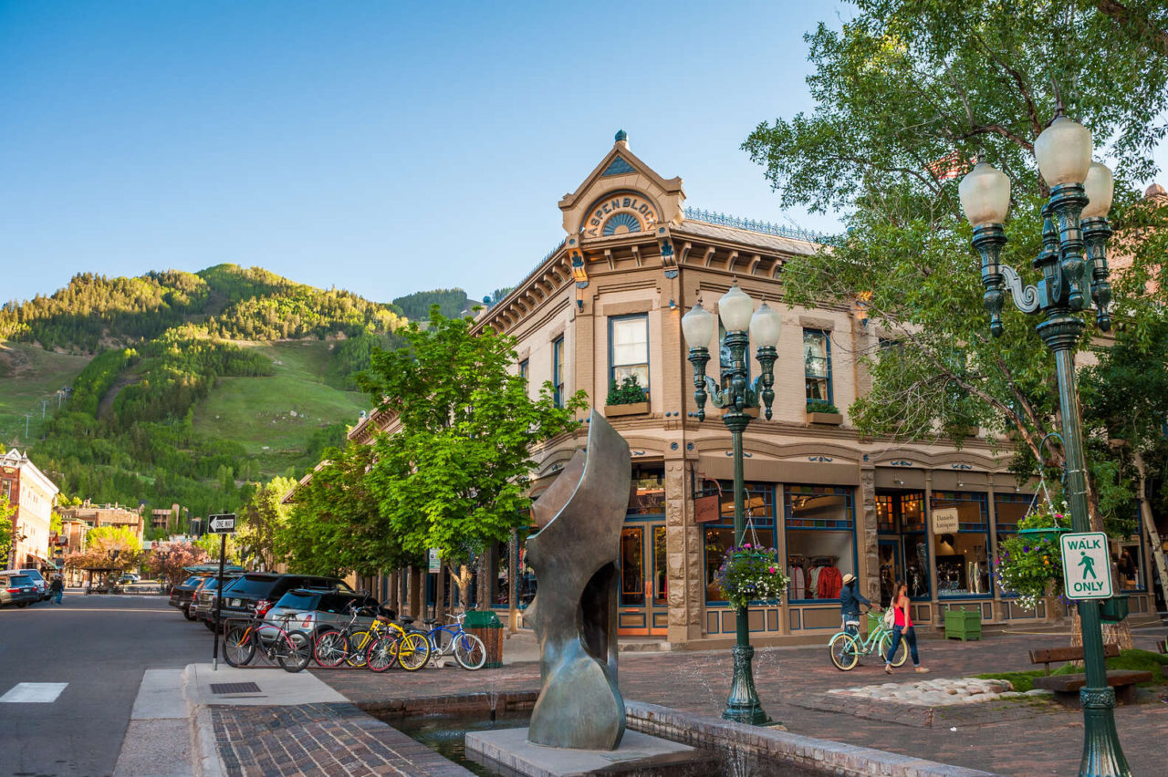 downtown aspen corner on galena street with an old building and green lush aspen mountain in the background