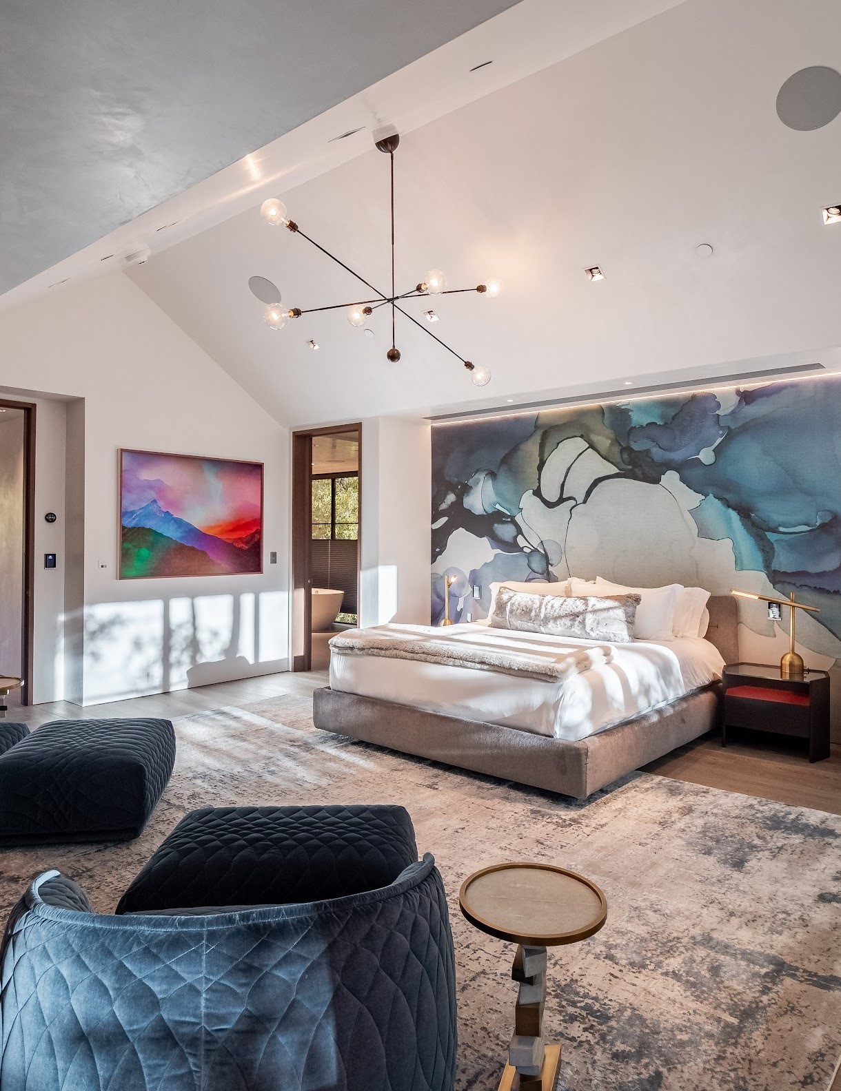 Downtown Aspen lodge bedroom with king bed, watercolor art accent wall and modern light fixture