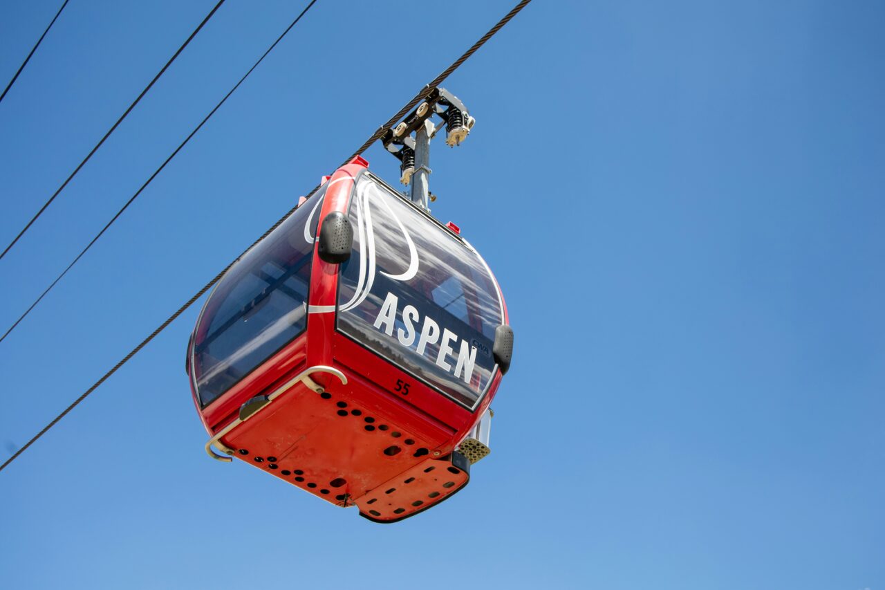 red gondola with an aspen logo with a blue sky background