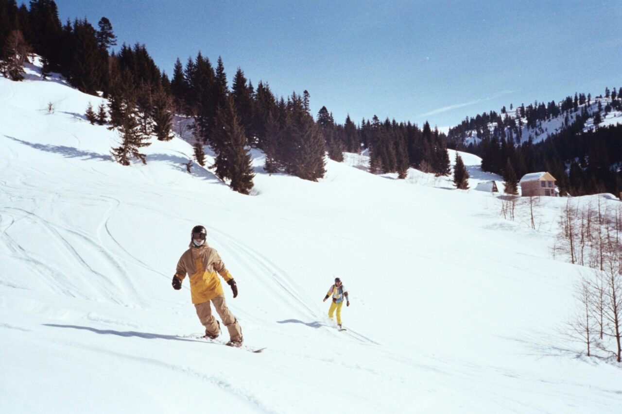 snowboarding man and kid with blue skies and trees in background